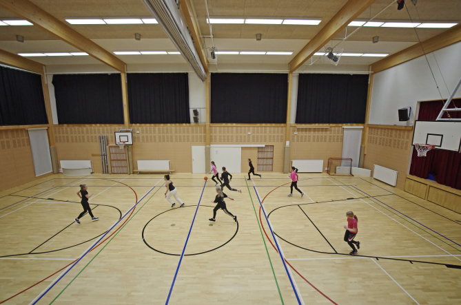 Keskuskoulun yläasteen tytöt pelaamassa koripalloa liikuntatunnilla Virtaalan liikuntasalissa